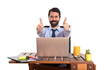 Businessman in his office with thumb up